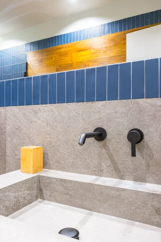 Bagno di Santopaolo 3, piastrelle blu, lavabo in pietra e rubinetti neri