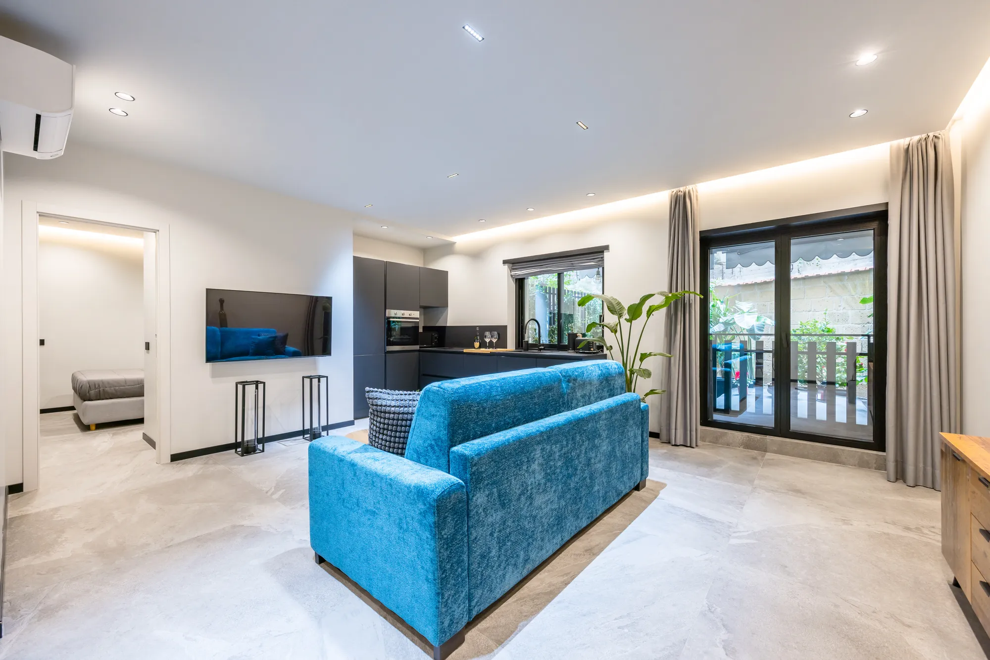 Salone di Santopaolo 4, divano blu, TV e porta finestra sul balcone